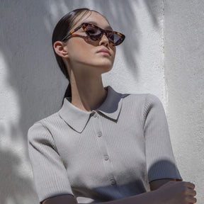 a woman wearing sunglasses sitting on a bench 